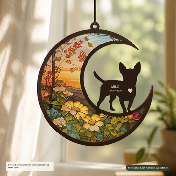 Personalized Chihuahua memorial suncatcher with dark walnut wood moon and pet silhouette, frosted acrylic sunset-garden artwork, the name Milo, and dates 2012 to 2025 in a warm window