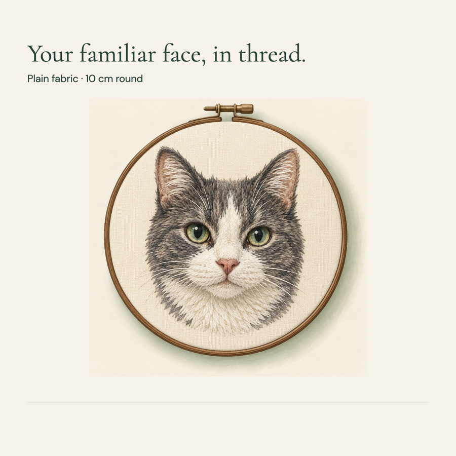 Gray and white cat portrait in a round plain fabric embroidery hoop.