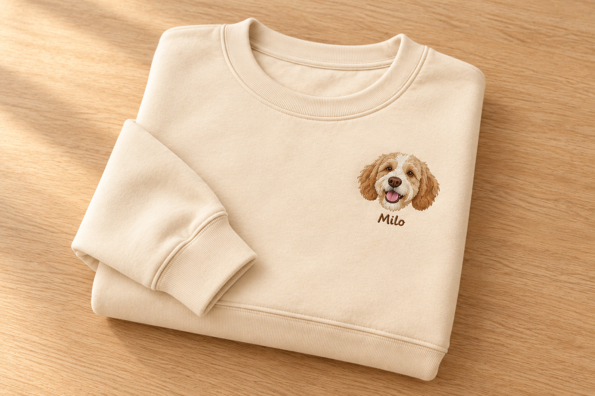 Folded apricot crewneck showing Milo portrait and name with the neckline, cuff and hem in view.