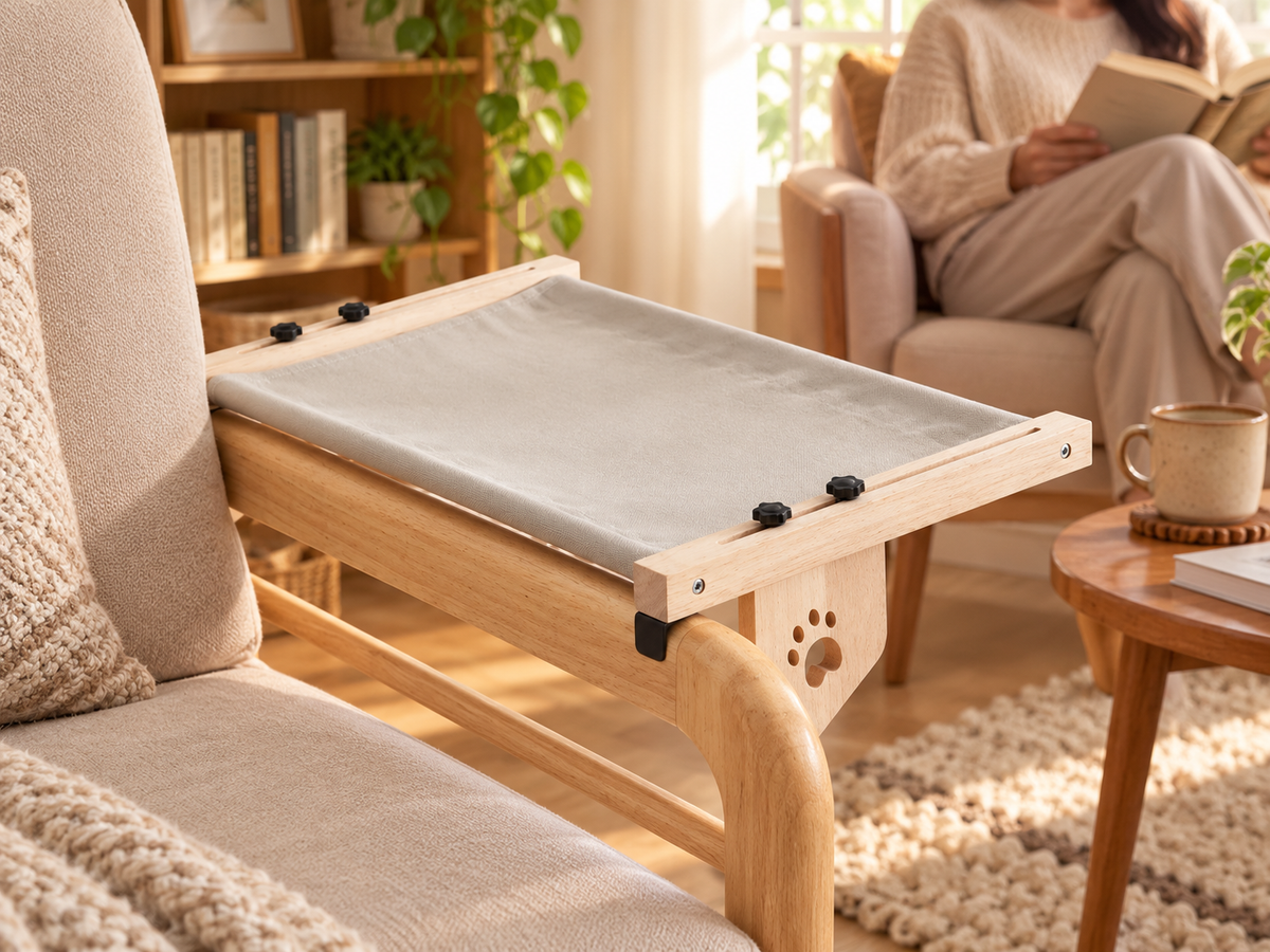 View of a grey wooden-frame hammock supported on a reading-chair arm.