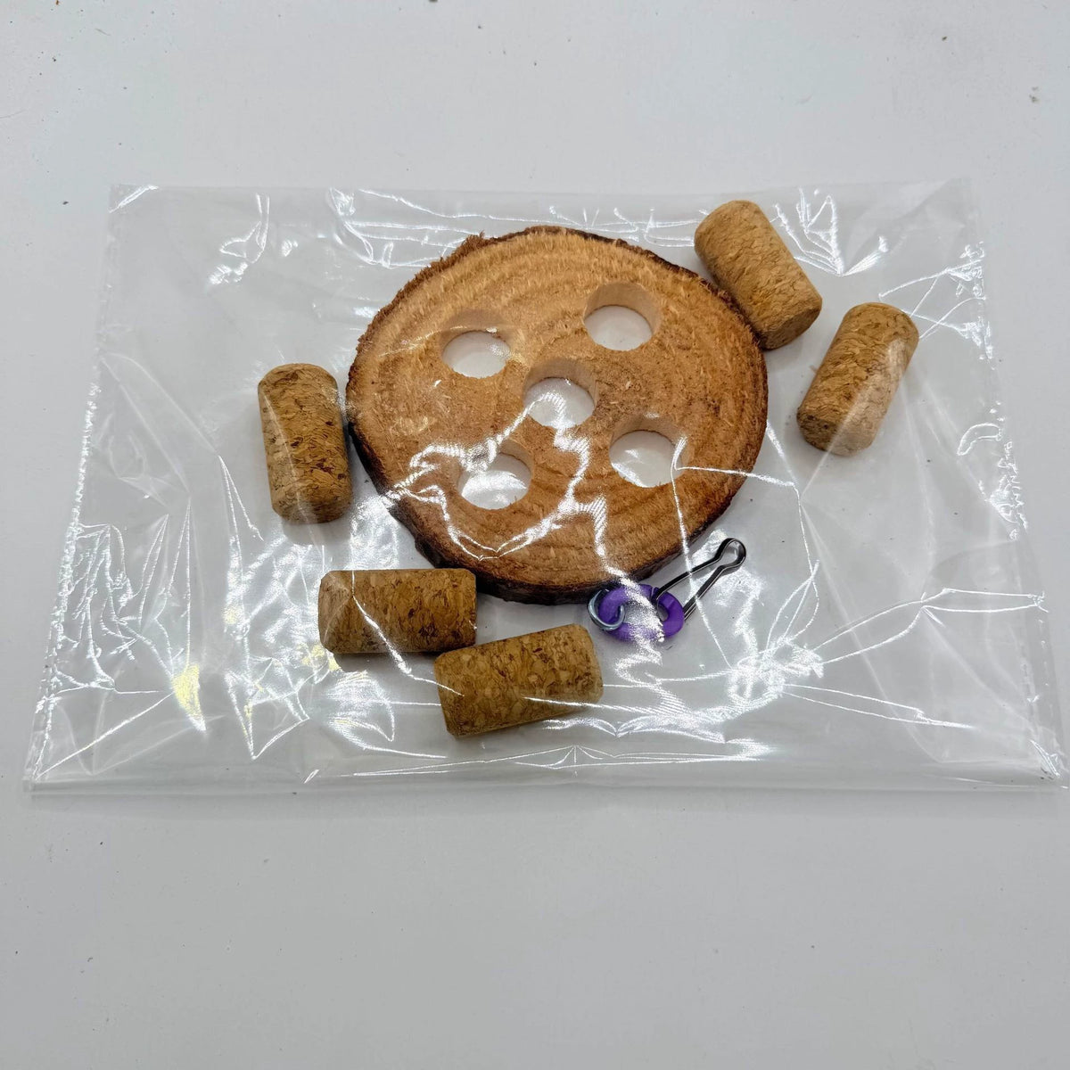 Component presentation showing one five-hole wood disk, five loose corklike pieces and purple-link hanging hardware.