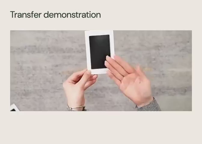 A white-frame black clean-touch transfer pad used with a dog paw.